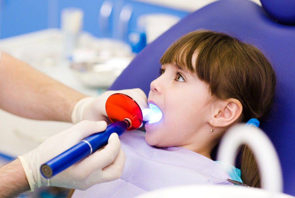 little girl with open mouth receiving dental filling drying